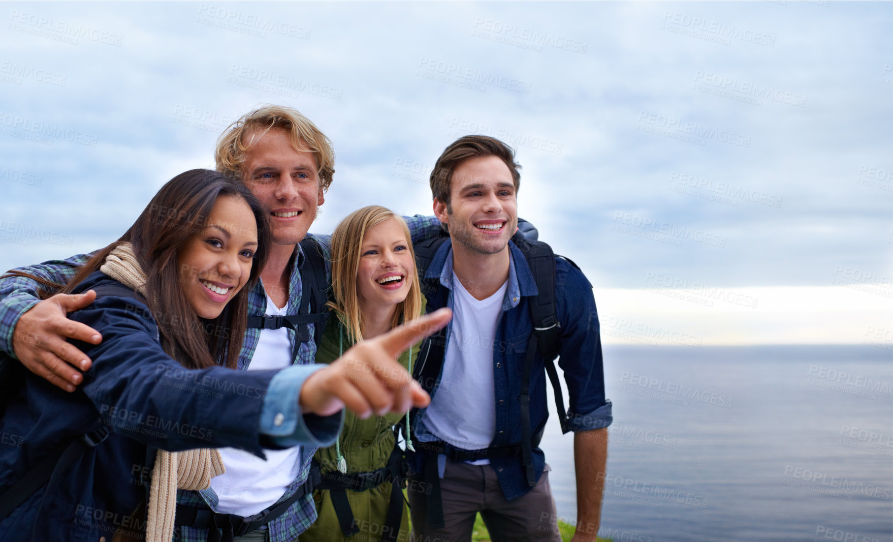 Buy stock photo Friends, group and happy on mountain top for hiking, adventure and pointing to location, travel and sightseeing. Happy young people with backpack and excited to explore, trekking or outdoor journey 