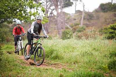 Buy stock photo A pair of young cyclists enjoying the outdoors and keeping fit mountain biking