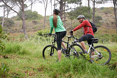 Buy stock photo A couple looking at each other while biking together in the outdoors