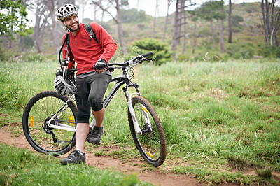 Buy stock photo An attractive male cyclist leaning against his bike in the outdoors