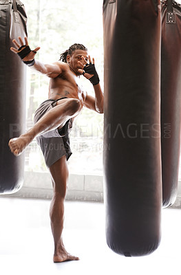 Buy stock photo Man, kick boxing and bag with training, foot and combat for exercise with balance, power and precision in gym. African athlete, person or fighter with workout, fitness or strike for challenge in dojo