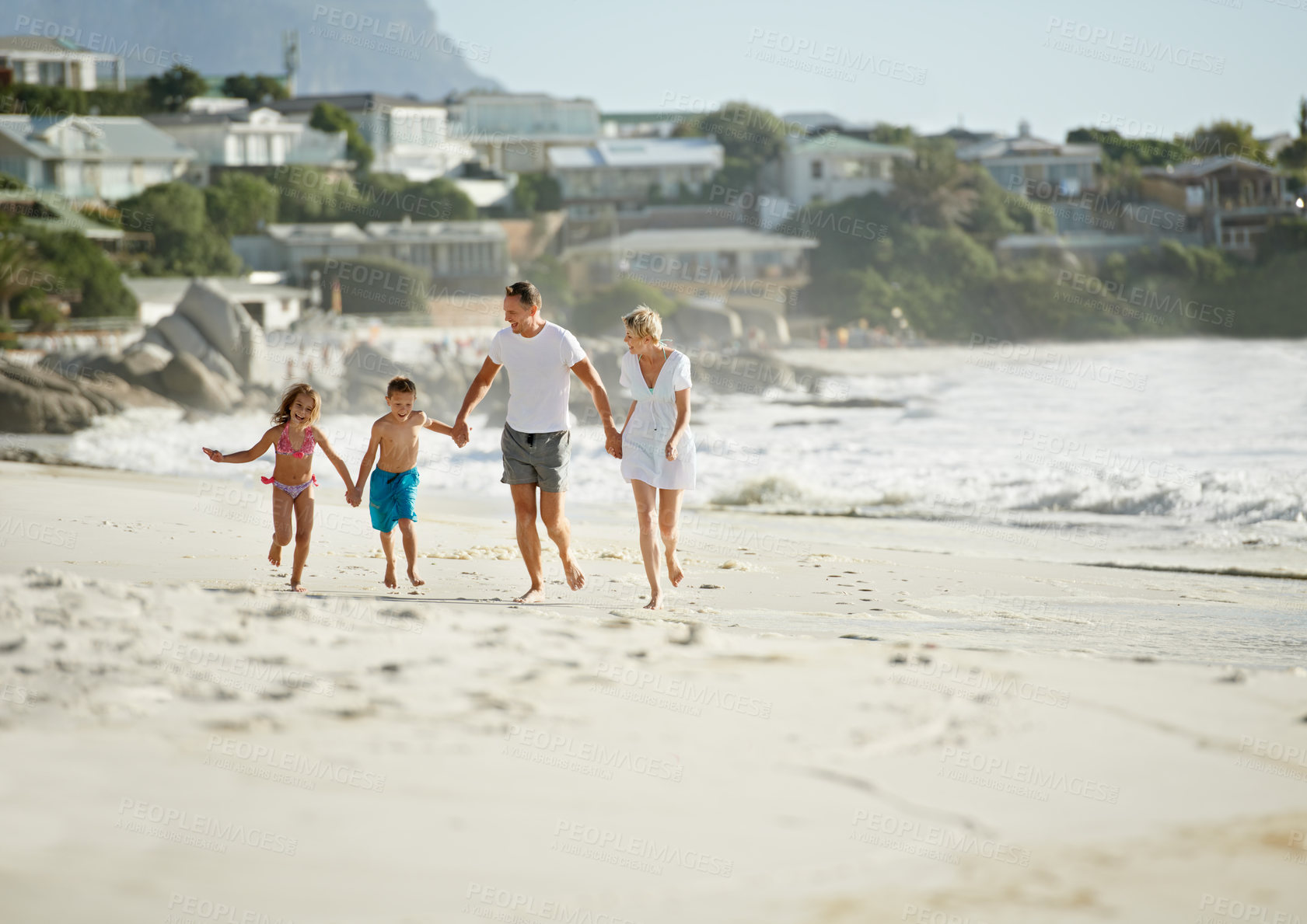 Buy stock photo A happy young family walking down the beach together in the sunshine