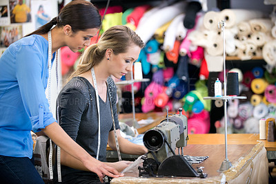Buy stock photo Two women working on a garment at a workbench inside their fabric shop