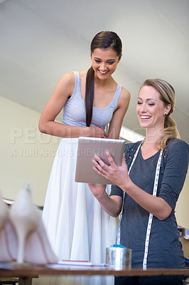 Buy stock photo A dressmaker showing her client something on a digital tablet inside a fabric shop