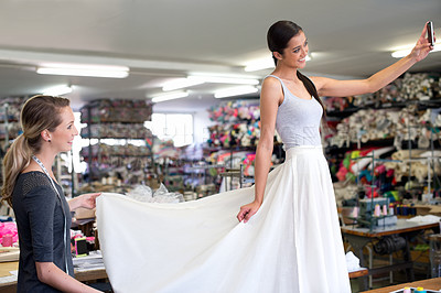 Buy stock photo A young woman in a fabric shop trying on a skirt made for her by a seamstress