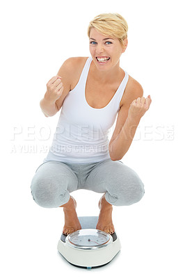 Buy stock photo A young blond woman standing on a scale with her arms raised in celebration