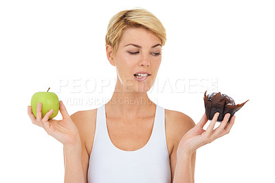 Buy stock photo Cropped shot of a young woman holding an apple and sweet treat looking indecisive-Isolated image