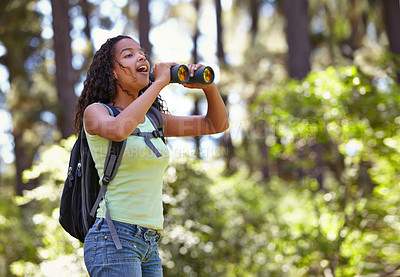 Buy stock photo Happy girl, binoculars and nature with backpack for sightseeing, explore or outdoor vision. Young female person, child or teenager enjoying sight, adventure or bird watching and search in forest
