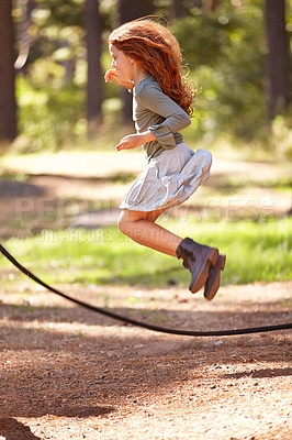 Buy stock photo Jump, rope and girl outdoor for game in forest, park or playing on summer, holiday and vacation. Child, skipping and energy for fun activity in nature with trees in backyard or garden with kid in air