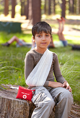 Buy stock photo Child, portrait and first aid for hurt arm with sling on bruise for medical treatment outdoors on tree trunk. Kid, emergency kit and bandage for muscle sprain, injury and camp accident in nature.