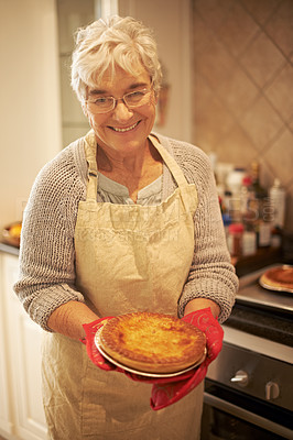 Buy stock photo Elderly lady, pie and smiling in kitchen at home for baking, cooking or retirement leisure. Happy, and proud senior person or grandmother with glasses for food recipes, meals and hobby in house  