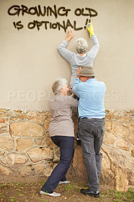 Buy stock photo Shot of mischievous pensioners spray-painting graffiti on a wall