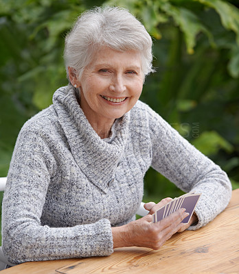 Buy stock photo Senior woman, portrait and outdoors playing cards, happy and game of bridge at park, garden or backyard. Elderly female, smile and poker at table for retirement fun on patio, porch or nursing home