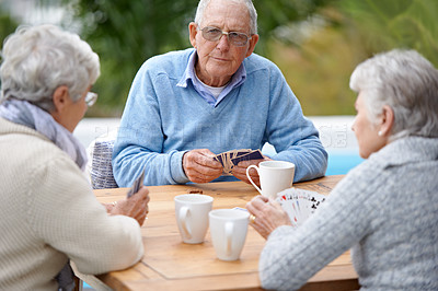 Buy stock photo Poker, playing cards and senior group in retirement, outdoor and relaxed in garden, backyard and terrace. Elderly people, bridge and smile with coffee, table and outside for relaxation, fun and games