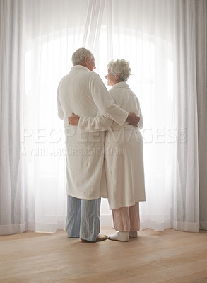 Buy stock photo Senior couple, hug and relaxing by window in retirement, love and bonding in pajamas on holiday. Elderly people, back and embracing for affection in marriage, romance and morning routine at home
