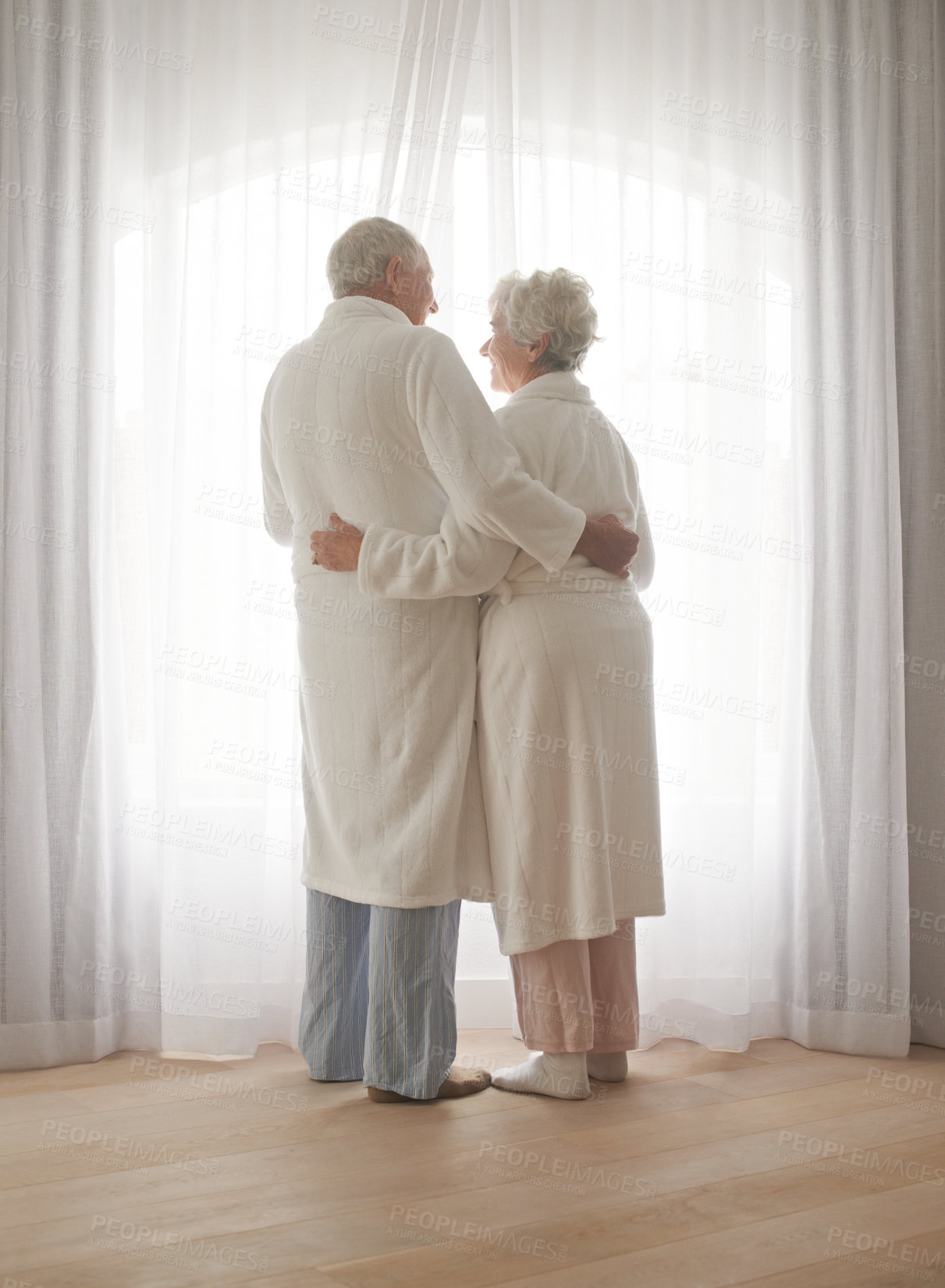Buy stock photo Senior couple, hug and relaxing by window in retirement, love and bonding in pajamas on holiday. Elderly people, back and embracing for affection in marriage, romance and morning routine at home