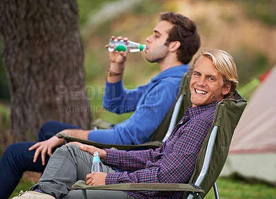 Buy stock photo Smile, nature and portrait of men camping in outdoor field, woods or forest on vacation. Happy, travel and young male friends relaxing on chairs in park for holiday, adventure or weekend trip.
