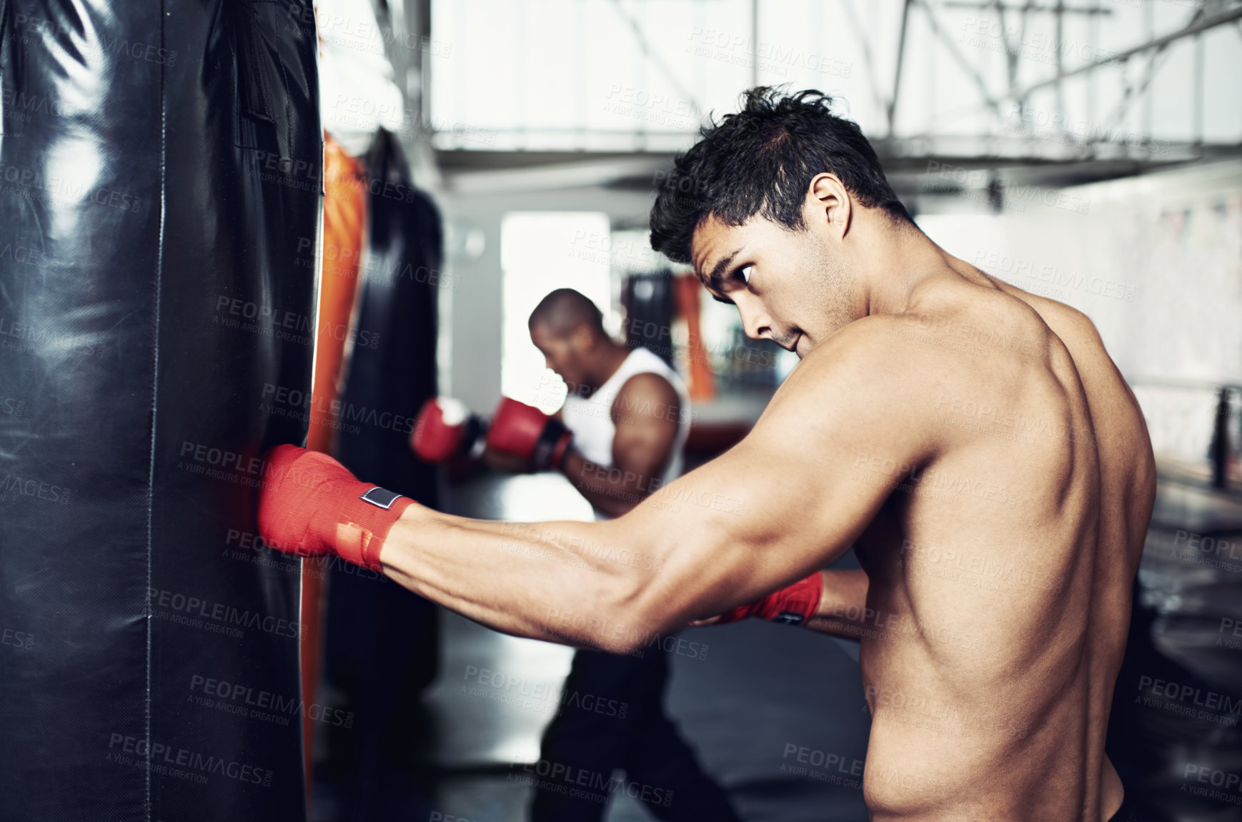 Buy stock photo Fitness, punching bag and man with boxing gloves at a gym for training, resilience or performance. Sports, body and male boxer profile with punch practice for strength, energy for fighting exercise