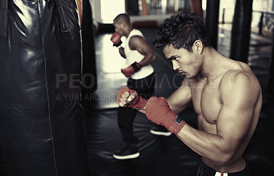 Buy stock photo Shot of a young male boxers training on heavy bags