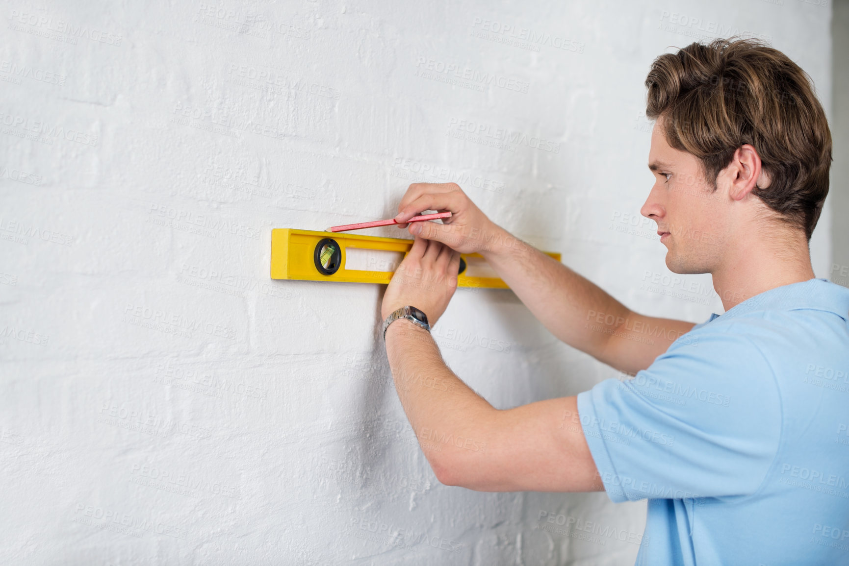 Buy stock photo Side view of a young man doing some measurements along a wall