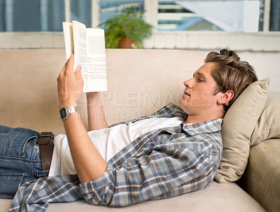 Buy stock photo Home, man and reading with book on couch for education, knowledge and literature to relax and rest. Living room, information and novel with story for entertainment, fantasy and mental health