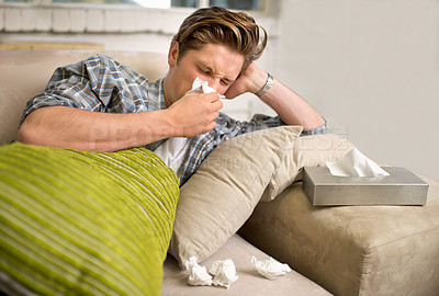 Buy stock photo Virus, influenza or man sneezing into tissue on sofa with cold, bug or hay fever at home. Flu, allergies or person with toilet paper for viral infection, bacteria or coughing with sinusitis in house