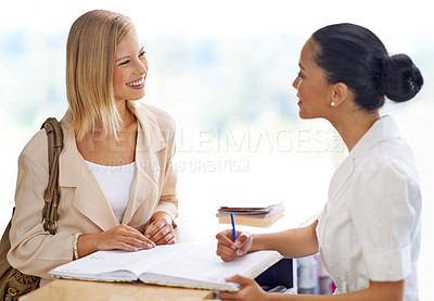 Buy stock photo Receptionist checking in a woman by her desk for an appointment, meeting or reservation at spa. Happy, conversation and secretary writing in book for signing in at counter with female person in salon