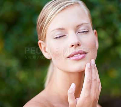 Buy stock photo Skincare, beauty and a woman touching face in a garden nature or backyard. Content, wellness and a young lady feeling skin for moisturizing, satisfaction or wellbeing glow from a spa treatment