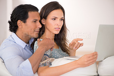 Buy stock photo A husband and wife browsing the web while sitting together on the sofa
