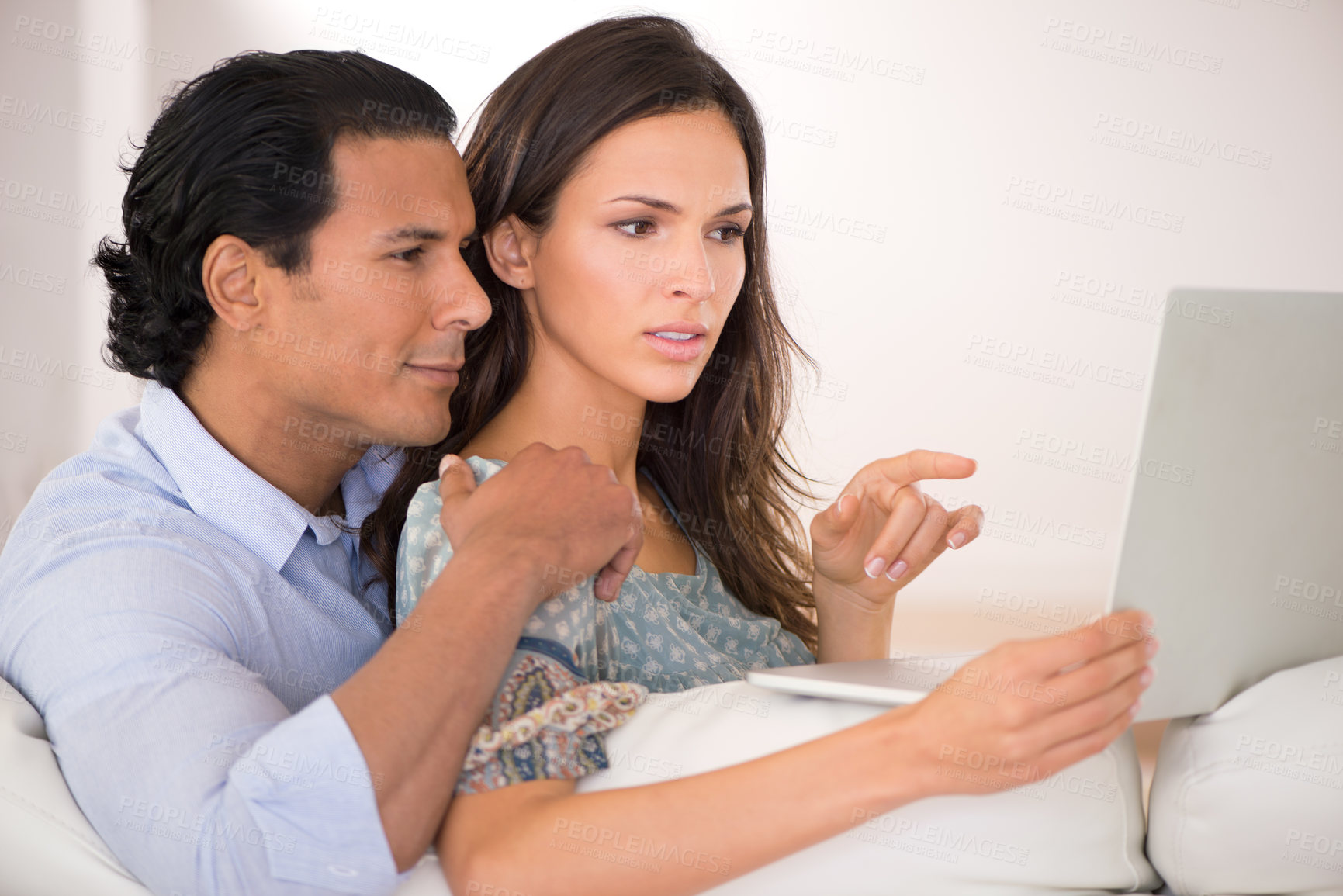 Buy stock photo A husband and wife browsing the web while sitting together on the sofa