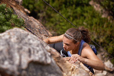Buy stock photo Shot of a young woman climbing a mountain rockface