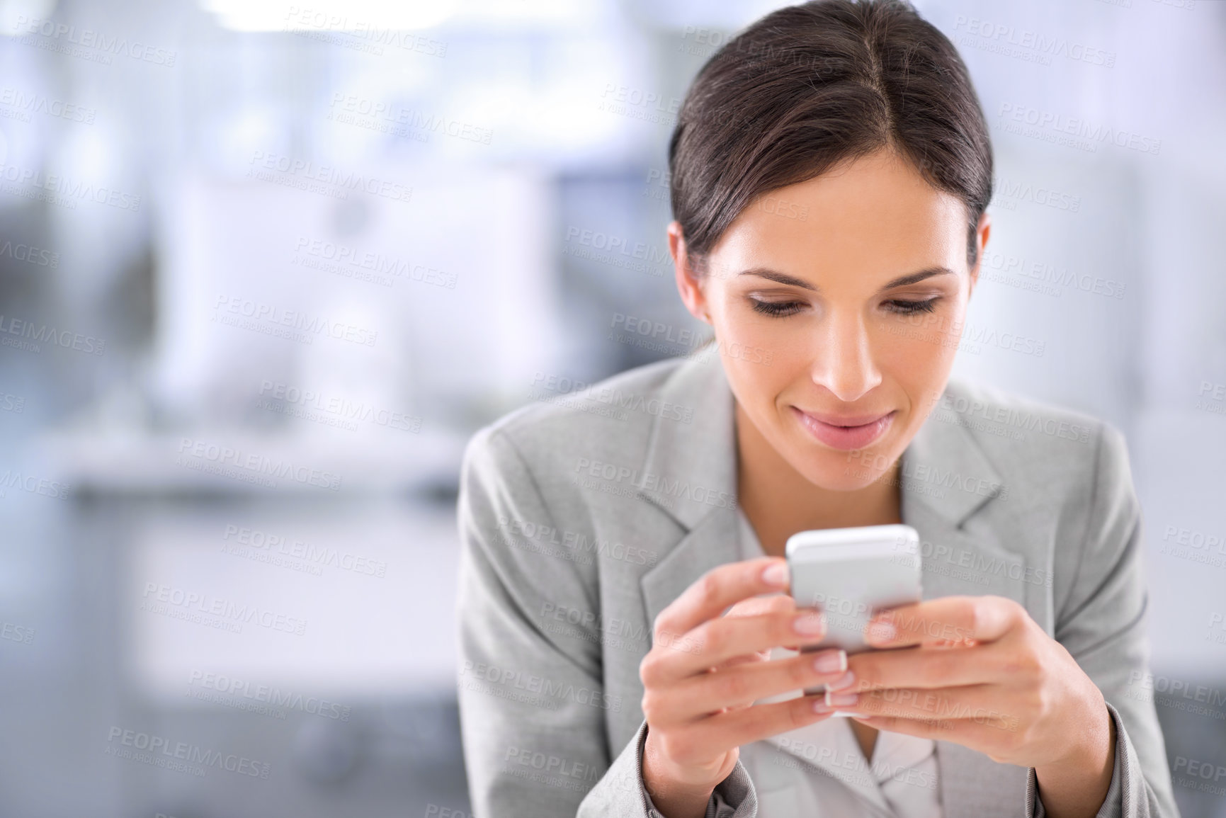 Buy stock photo Businesswoman browsing social media on a phone at work in a modern office. Female chatting online, signing up to a dating app or social website. Lady reading updates on the internet while on a break