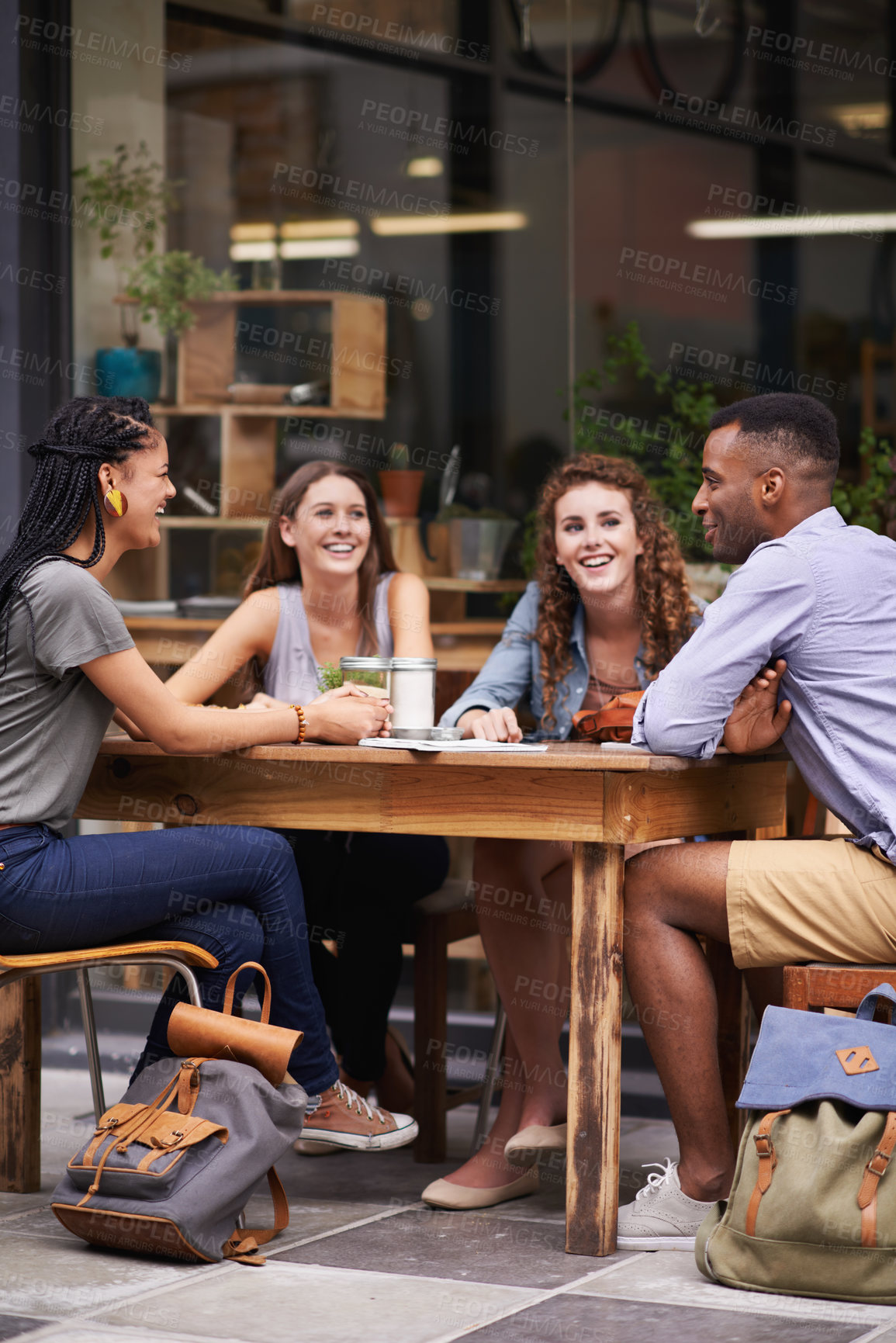 Buy stock photo A group of young friends sitting outside at a sidewalk cafe