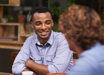 Buy stock photo A handsome young man sitting with a friend at a cafe