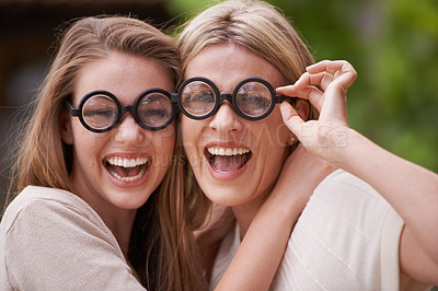 Buy stock photo Women, mother and daughter with funny glasses in garden for comic joke, laughing and hug in portrait. People, girl and mature mom with funny smile, family or play with bonding for connection at house