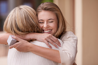 Buy stock photo A daughter embracing her mother after receiving a gift
