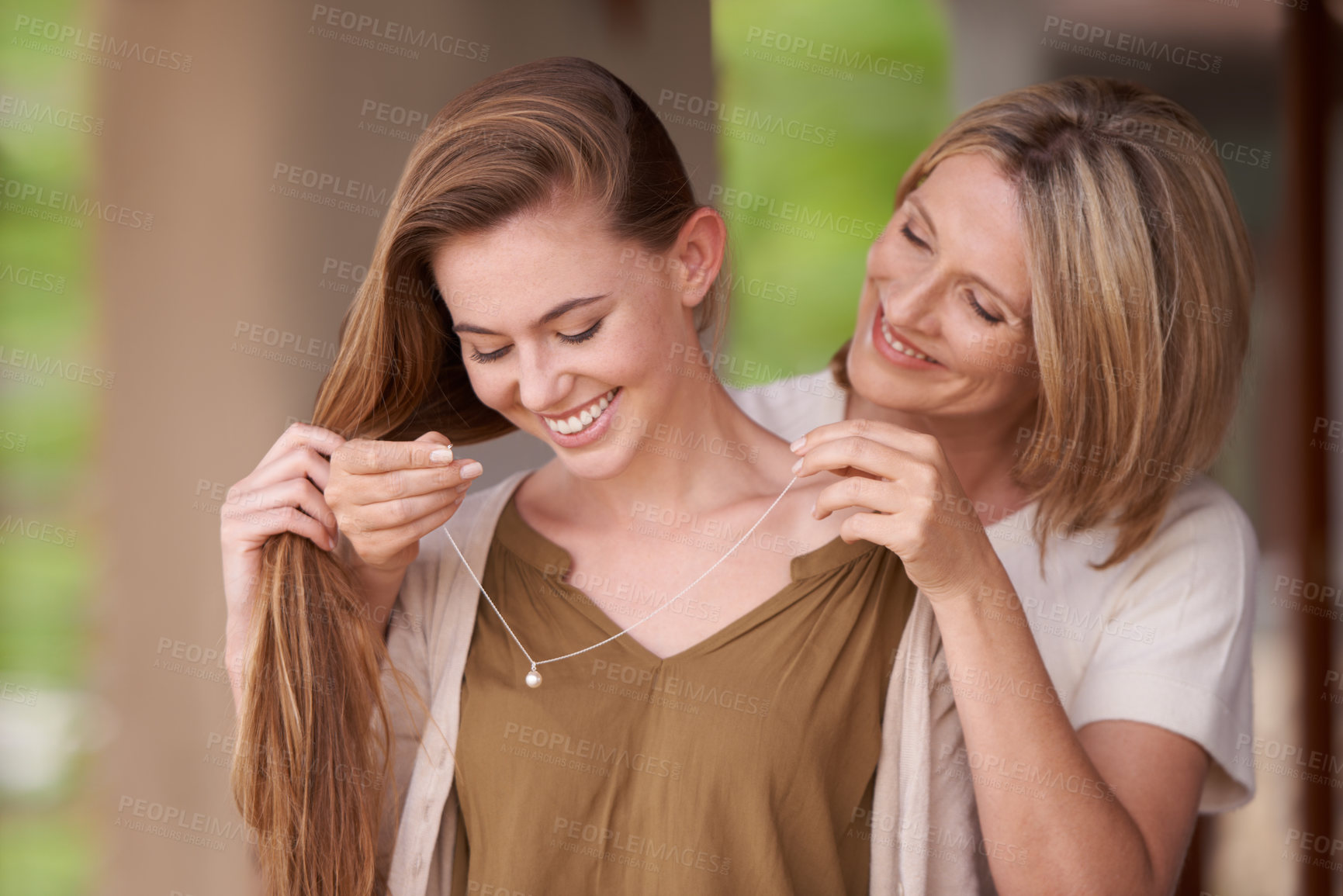 Buy stock photo A mother lovingly putting a necklace around her daughter's neck