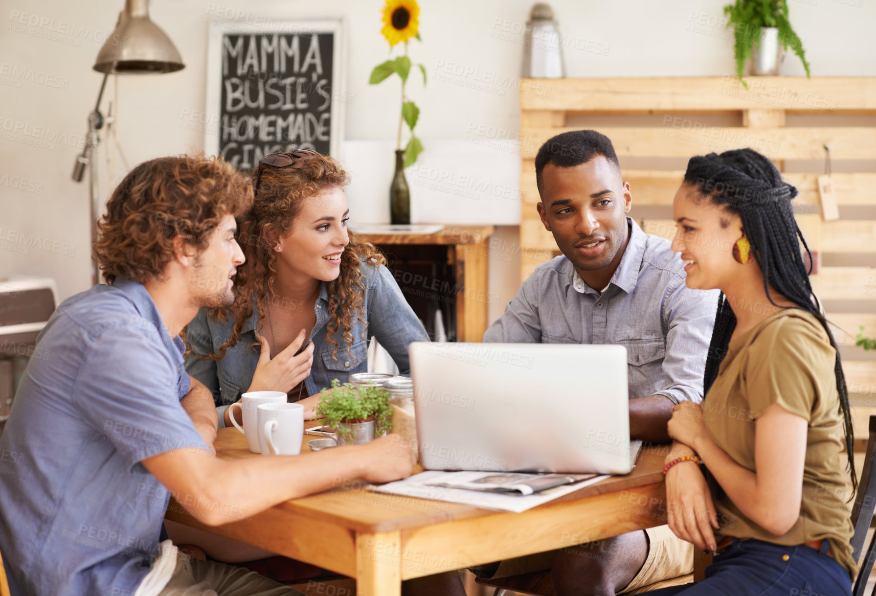 Buy stock photo A group of friends sitting together in a coffee shop with a laptop