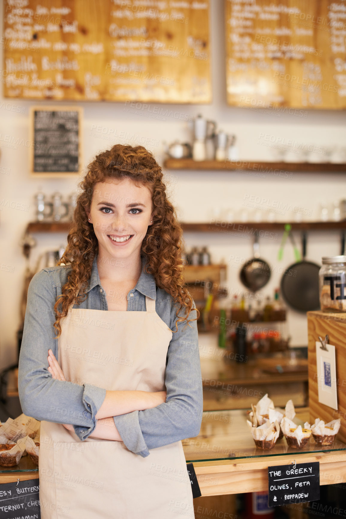 Buy stock photo An attractive young barista standing at a cafe counter