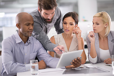 Buy stock photo Shot of a group of businesspeople discussing the contents of a tablet during a meeting