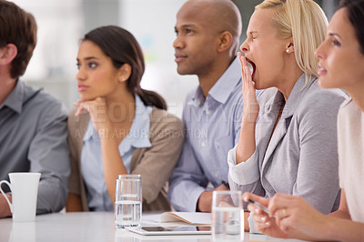 Buy stock photo Shot of a businesswoman yawning during a meeting with her colleagues