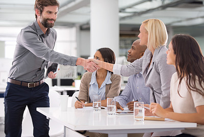 Buy stock photo Shot of a businessman shaking the hands of his colleagues sitting on a panel