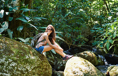 Buy stock photo Woman, hiking and river in tropical rainforest with smile for adventure, journey and rocks with backpack. Girl, outdoor and bag by water, earth and trees in jungle on holiday with freedom in Colombia