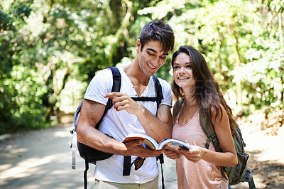 Buy stock photo Couple, map and point for hiking in woods with reading for thinking, holiday and ideas on path. Man, woman and bag for trekking, direction and search in rainforest with book for location in Colombia