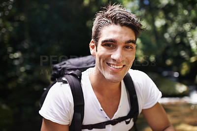 Buy stock photo Shot of a handsome young man hiking in the forest