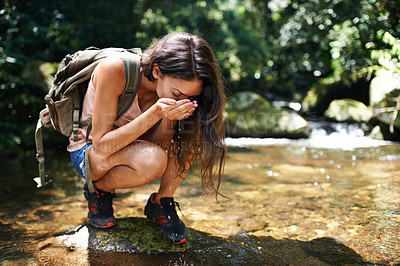 Buy stock photo Drinking water, nature and woman by river in forest for thirst on adventure, trekking and explore outdoors. Travel, hiking and person by lake for health and wellness on holiday, vacation and journey