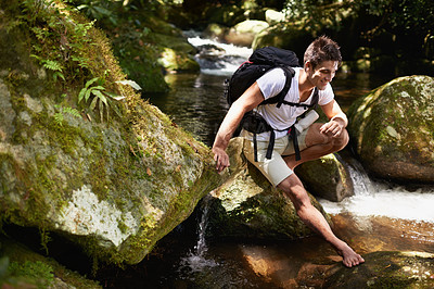 Buy stock photo Man, hiking and river in tropical jungle with smile for adventure, journey and rocks with backpack. Person, outdoor and bag by water, earth and trees in rainforest on holiday with freedom in Colombia