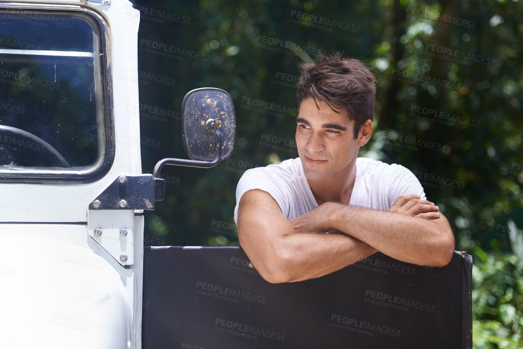 Buy stock photo A handsome young man leaning on his car door while out in the forest