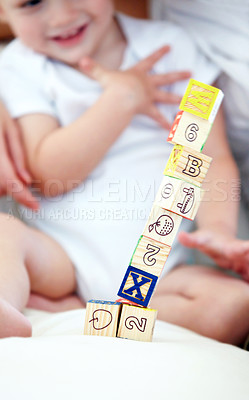 Buy stock photo Baby, kid and playing with blocks for learning, smile and happy in home nursery on bed. Toddler, wood and child with toys for alphabet, education and development of cute boy with numbers closeup