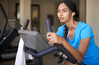 Buy stock photo Woman, earphones and music for cycling, bike and stationary machine for workout at club. Female person, cardio and inspirational podcast for motivation, playlist and equipment for fitness and health